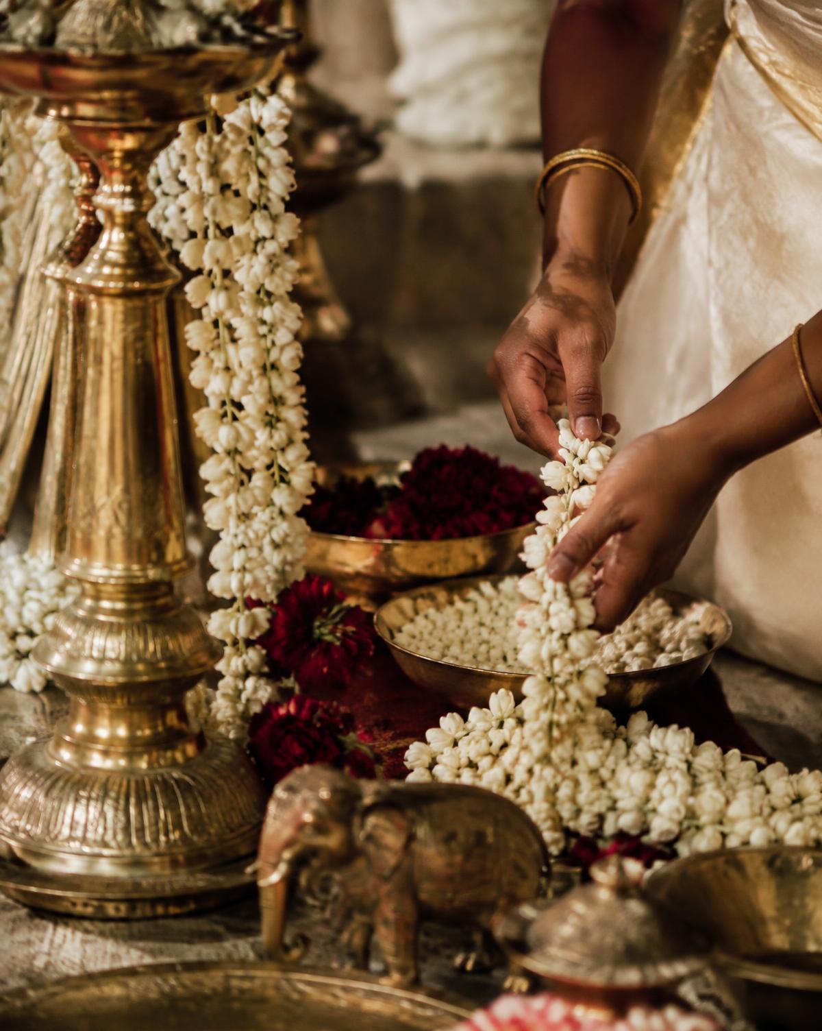 Artisan arranging jasmine garlands and brass decor